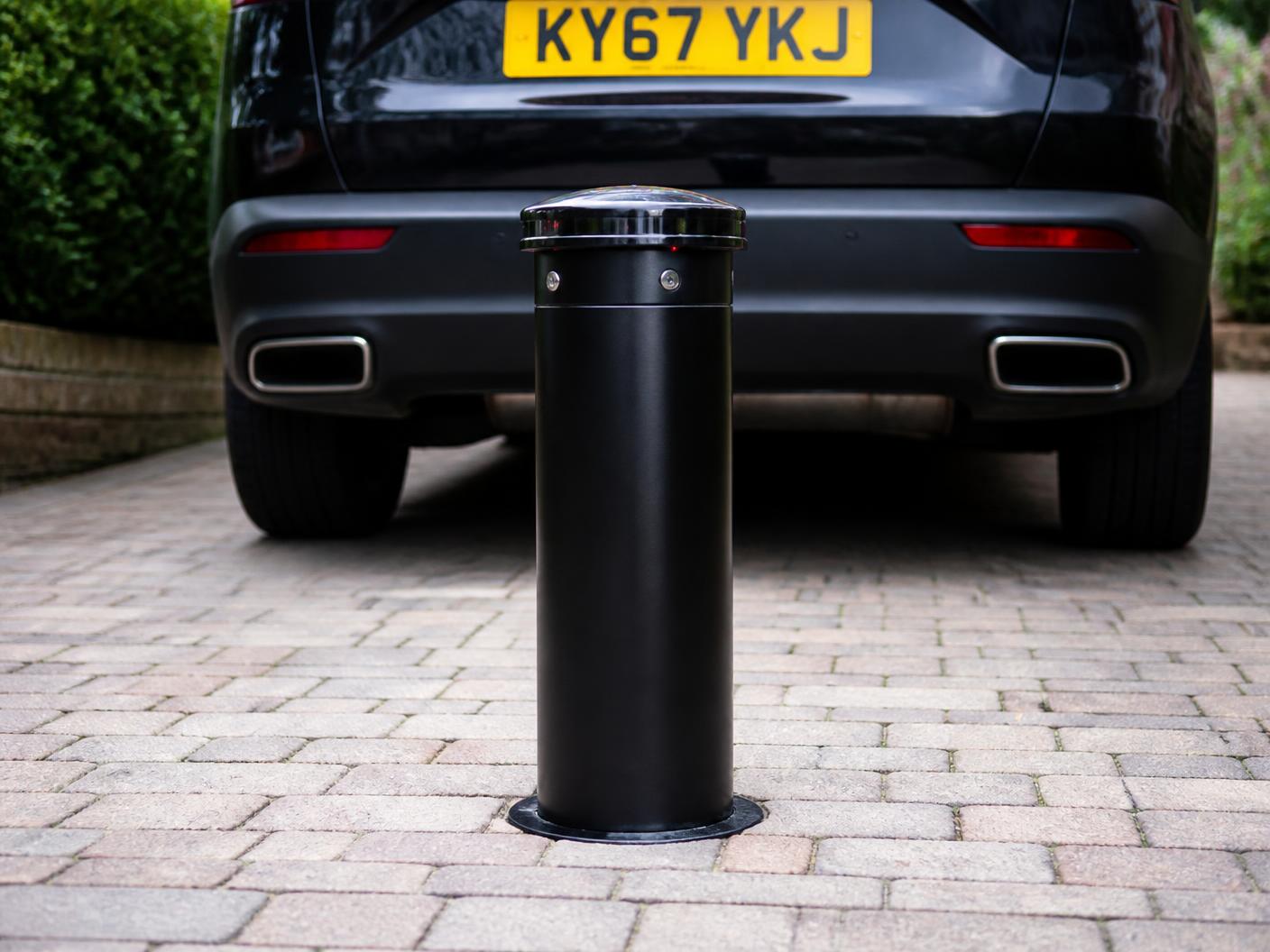 Raised telescopic bollard protecting a driveway